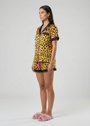 Woman wearing a leopard print outfit with pink slippers on a white background